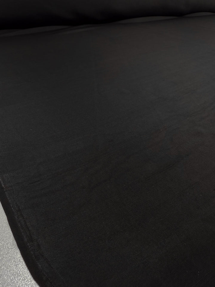 A close-up of Super Cheap Fabrics' Pure Silk Faille in Black (115cm), showcasing its smooth texture and delicate folds.