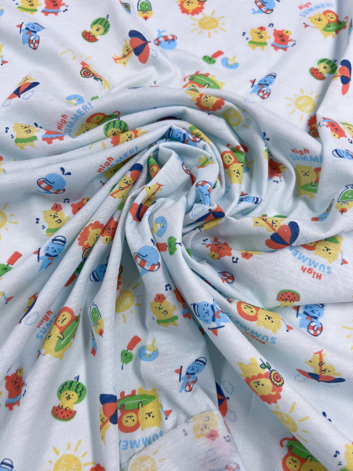 The Printed Jersey - Summer Times from Super Cheap Fabrics showcases a lightweight fabric adorned with a lively design. The pattern features vibrant cartoon animals alongside summer-themed icons, such as sun, ice cream, and beach balls, all set against a light blue background. The fabric is gathered in the center to create gentle folds.