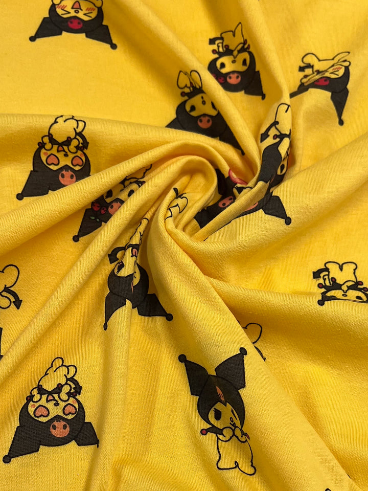 A close-up of the Printed Jersey - Pixy from Super Cheap Fabrics showcases a delightful yellow cotton jersey adorned with a whimsical pattern of cartoon animals in costumes, complete with capes and hats. The medium-weight fabric is artfully gathered at the center, forming an eye-catching spiral effect.