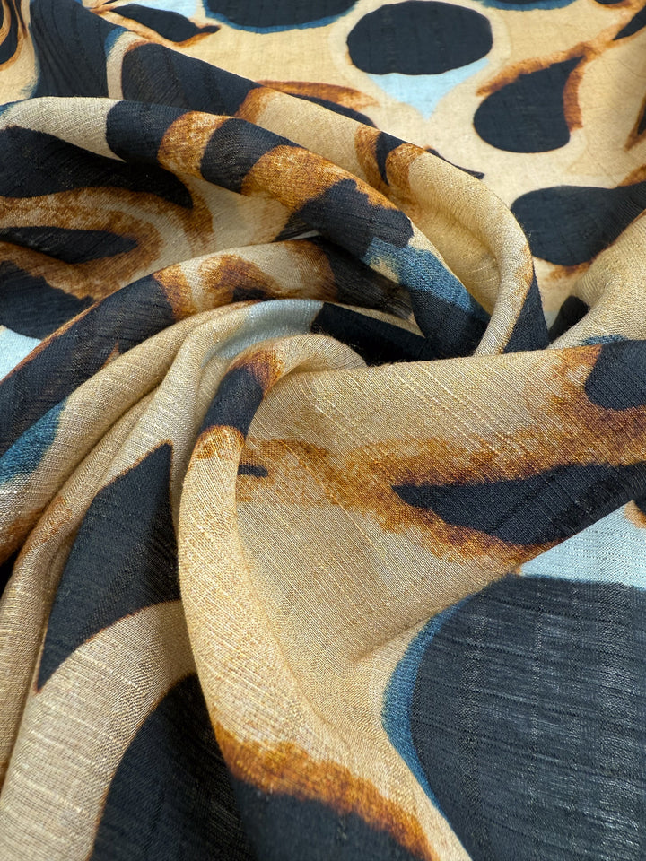 Close-up of Super Cheap Fabrics’ Textured Designer Cotton - Terra Dot (145cm), featuring a soft, lightweight drape with bold abstract animal print in black, tan, and brown shades.