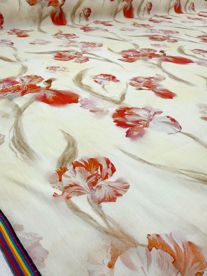 A close-up of Designer Cotton - Painted Petal by Super Cheap Fabrics, 145cm wide, shows cream fabric with red and pink floral patterns, greenish stems, and a multicolored edge in the lower left corner.