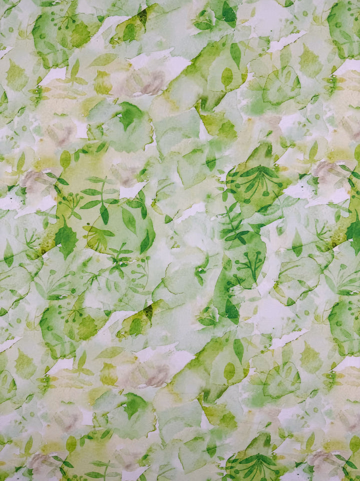 Designer Cotton - Garden Fade - 145cm by Super Cheap Fabrics features a watercolor green pattern with abstract leaves on white, offering a fresh, organic look—ideal for luxury sewing or designer cotton projects.