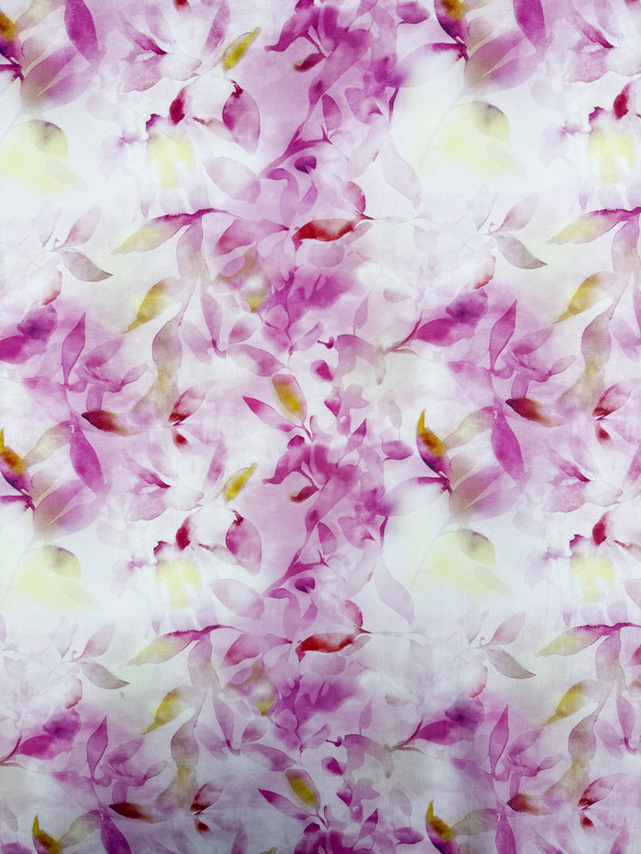 Designer Cotton - Bloom Drift by Super Cheap Fabrics features a delicate, painterly abstract floral print in soft pink, purple, yellow, and green on lightweight 145cm cotton with a light white background.