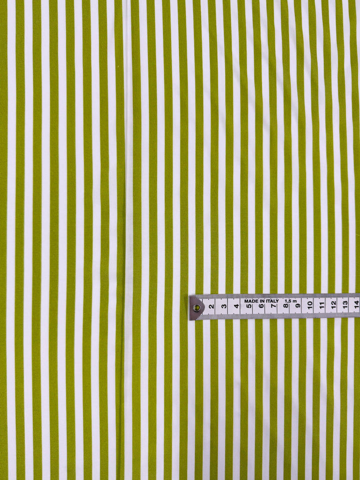 Super Cheap Fabrics’ Printed Rayon - Lime Pop Stripe - 140cm features yellow and white vertical stripes, shown with a metallic tape measure at the bottom right displaying up to 25 centimeters.