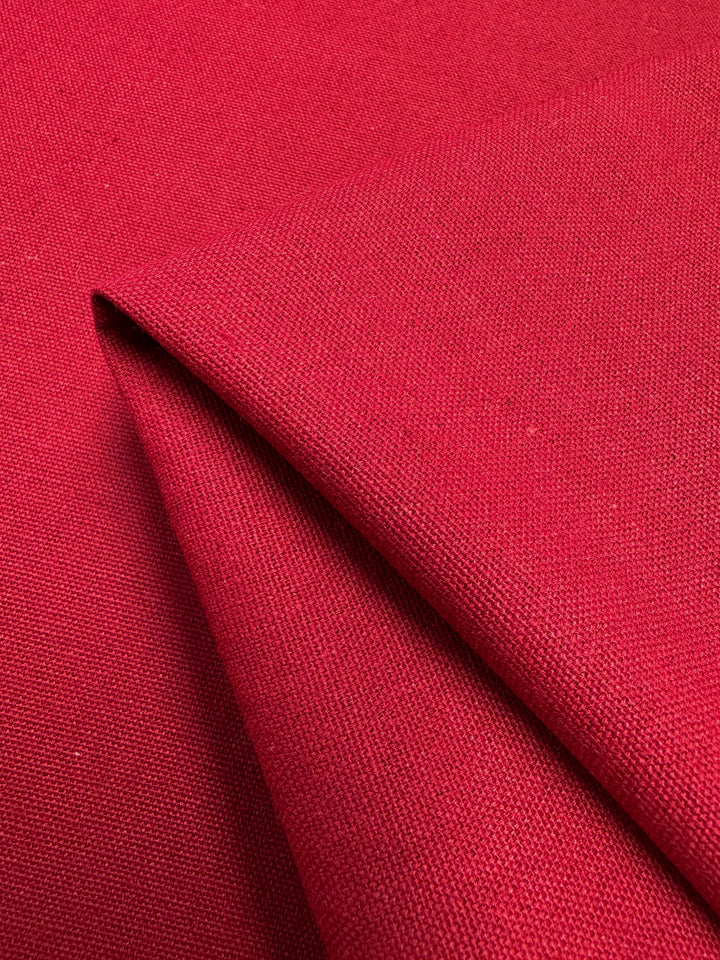 Close-up of a fold in a piece of Linen Blend - Salsa - 150cm by Super Cheap Fabrics. The textile has a slightly textured weave, and light shadows are cast along the fold, highlighting the material's thickness and structure.