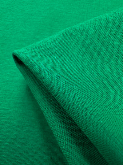 Close-up of folded Cotton Lycra - Green Tambourine fabric from Super Cheap Fabrics, featuring a visible weave texture ideal for crafting bodycon dresses. Width: 160cm.