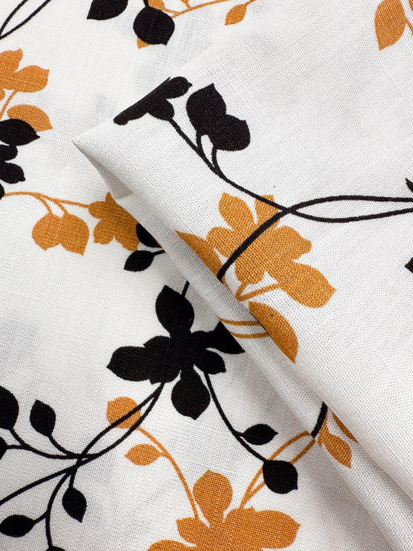 A close-up of Super Cheap Fabrics' Bamboo Rayon - Vine Whisper (150cm), showing its lightweight fabric with a floral print in black and mustard yellow, thin winding stems, and gentle folds highlighting its beginner-friendly design.