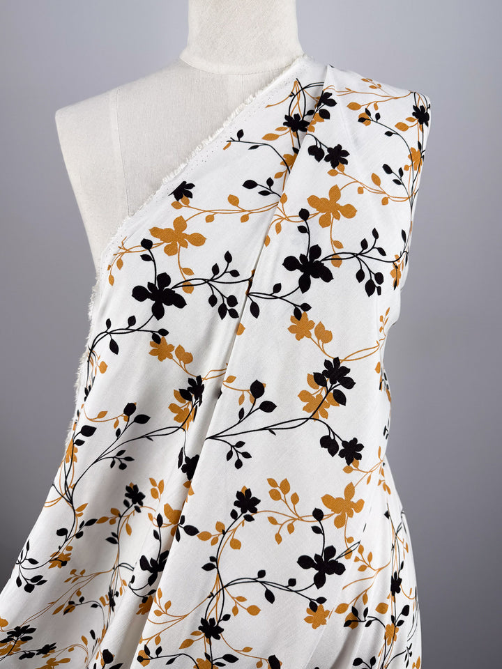 A mannequin displays Super Cheap Fabrics’ Bamboo Rayon - Vine Whisper (150cm), a beginner-friendly, lightweight fabric with a yellow-and-black floral vine pattern, set against a plain neutral background.