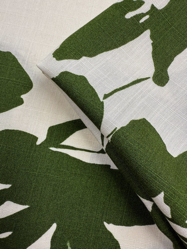 Close-up of Bamboo Rayon - Olive Bloom - 150cm by Super Cheap Fabrics, showcasing lightweight fabric with a green and white abstract leaf pattern on a textured surface.