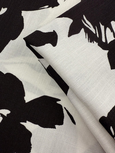 A close-up of Super Cheap Fabrics’ Bamboo Rayon - Jet Bloom (150cm) shows its lightweight feel and bold black-and-white abstract floral print, with visible weave—ideal for beginner-friendly sewing projects.