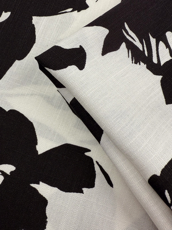 A close-up of Super Cheap Fabrics’ Bamboo Rayon - Jet Bloom (150cm) shows its lightweight feel and bold black-and-white abstract floral print, with visible weave—ideal for beginner-friendly sewing projects.