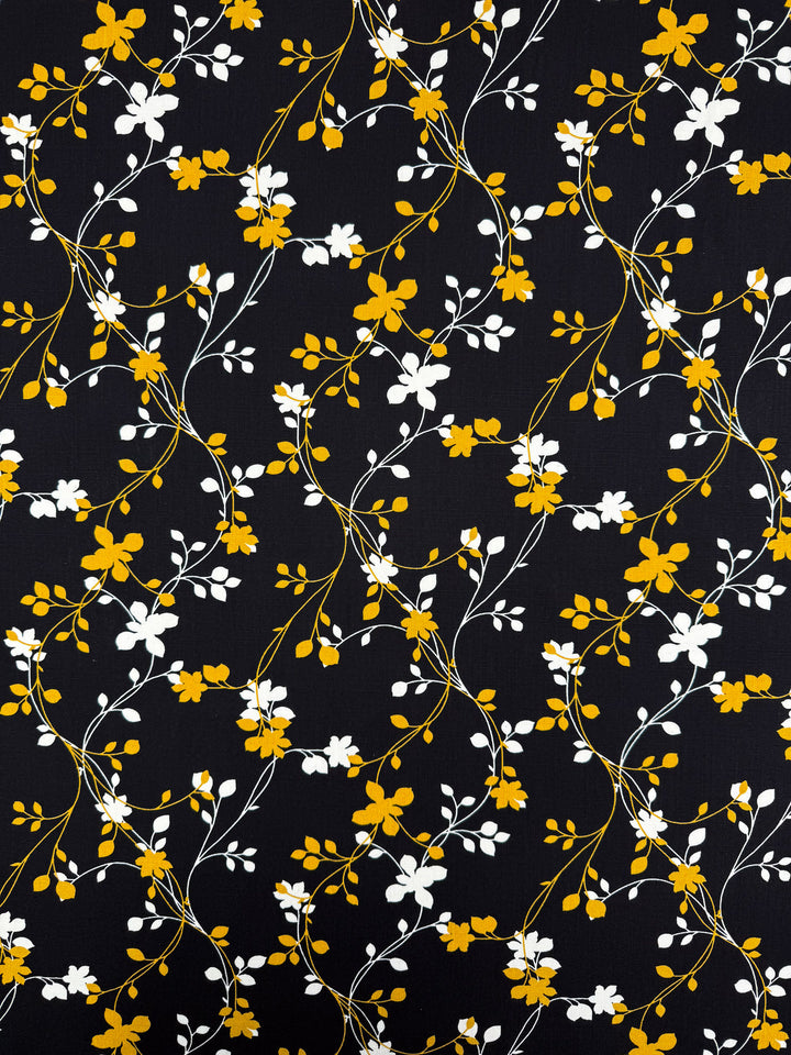 Super Cheap Fabrics’ Bamboo Rayon - Golden Vine (150cm) features a lively, seamless pattern of yellow and white flowers with green stems on black—ideal for lightweight fabrics and beginner-friendly sewing projects.