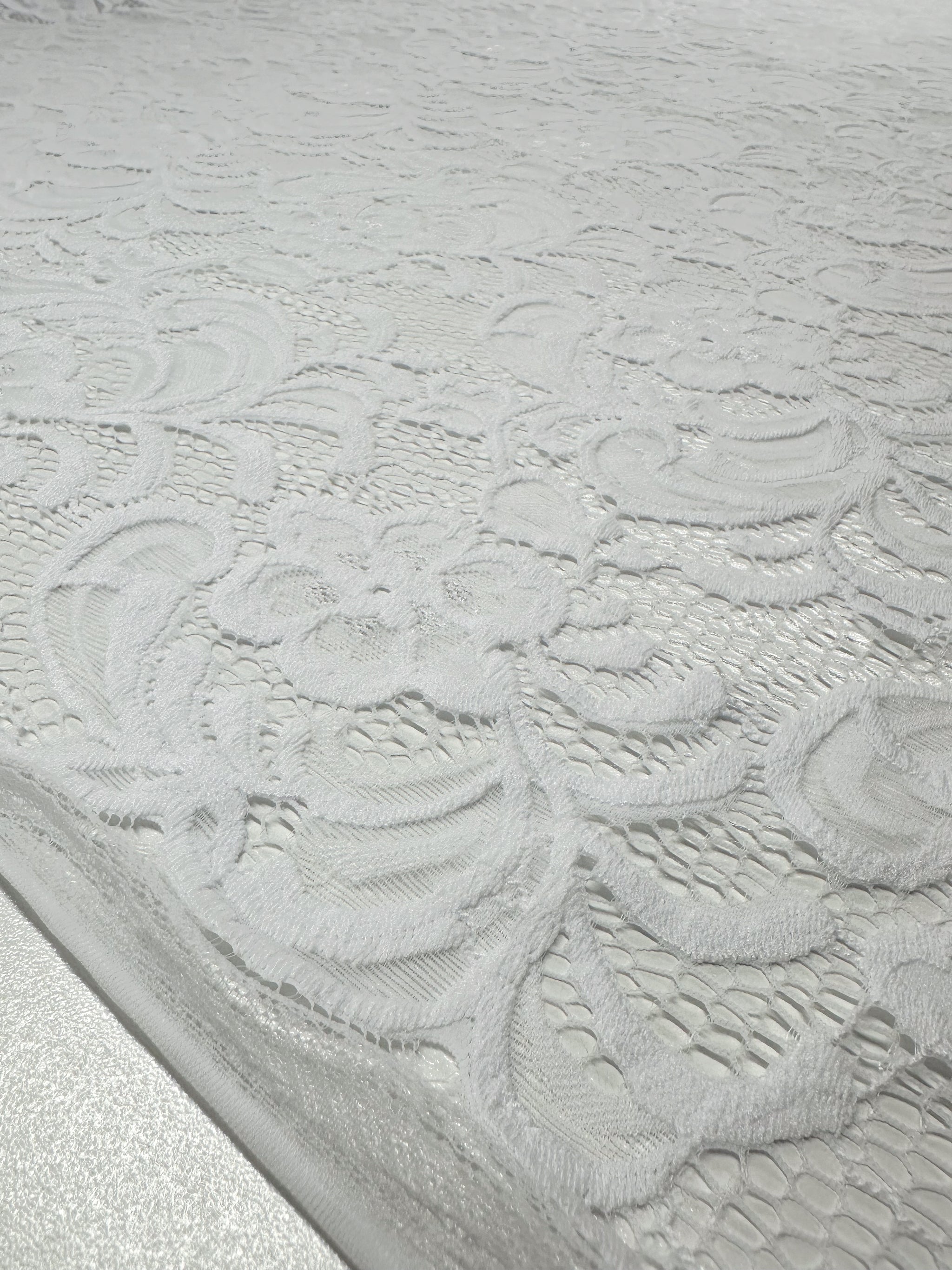 Close-up of Designer Lace - White - 145cm by Super Cheap Fabrics, showcasing an intricate floral pattern and delicate weaving, ideal for evening dresses. The lace spans the entire image, highlighting its elegant design.