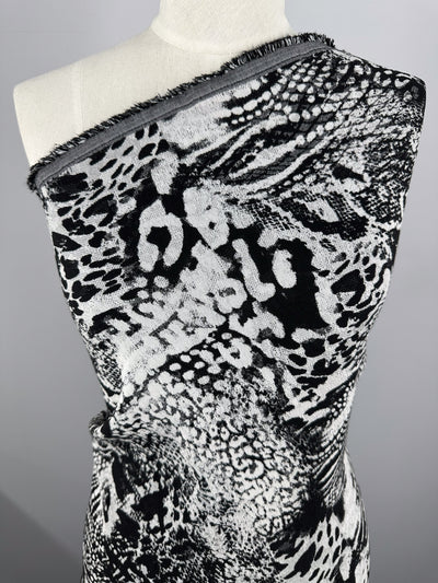 A close-up of a mannequin draped in Jacquard Bengaline - Survivor by Super Cheap Fabrics showcases a black and white abstract animal print with various spot-like shapes and textures on medium-weight stretch fabric, creating a dynamic visual effect.