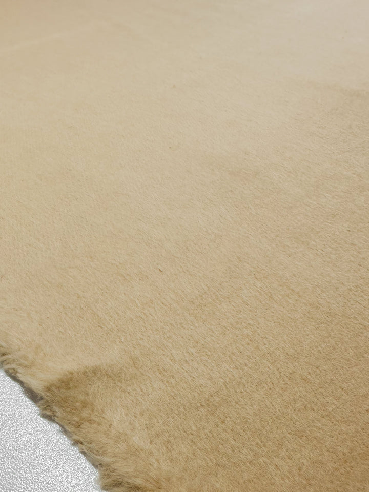 Close-up of the Wool Cashmere in Gray Sand by Super Cheap Fabrics, showcasing its luxurious softness and fuzzy texture laid flat. This 150cm fabric has a slightly frayed edge on the left, highlighting its uncut nature, while its surface emits an elegant warmth with a subtle sheen.