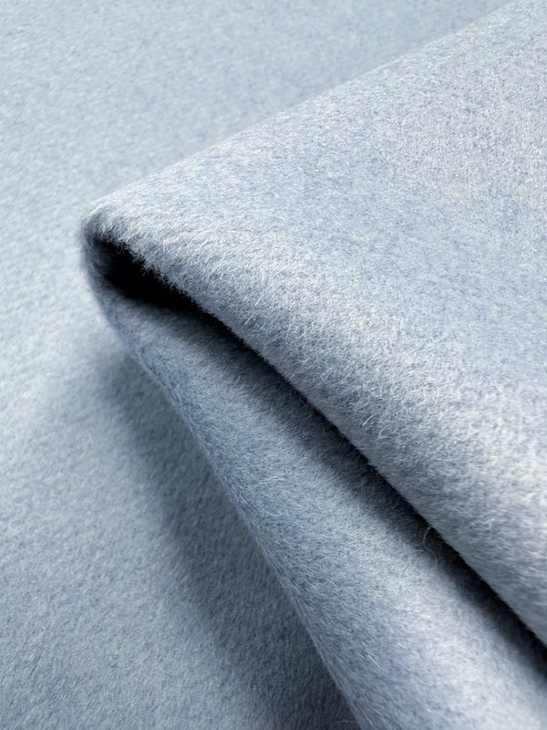 Close-up of the luxurious Wool Cashmere - Niagara Mist by Super Cheap Fabrics. The image highlights its folded, light blue texture, elegant design, and soft gradient.