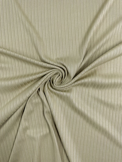 Close-up of medium weight Rib Knit - Hay from Super Cheap Fabrics in olive green. The swirl pattern at the center creates texture, with stretch fabric gathered to form gentle folds and shadows. Fabric width is 170cm.