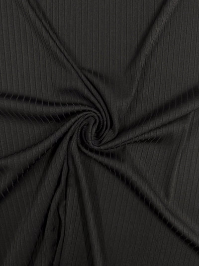 Close-up of Super Cheap Fabrics' Rib Knit - Black, a medium-weight fabric featuring subtle vertical ribbing. The stretchy and comfortable material is gathered at the center, forming an enchanting spiral pattern. Width: 170cm.