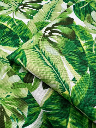 Close-up of Super Cheap Fabrics' Printed Canvas - Monsterra - 112cm, showcasing a detailed tropical design with lush green leaves in various shades, ideal for tote bags or home décor accents.