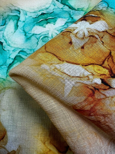 Close-up of the Designer Cotton - Mantis - 150cm by Super Cheap Fabrics featuring an abstract watercolor design. This fabric displays vibrant shades of teal, gold, and cream that mimic fluid brushstrokes. Its soft and subtly textured feel makes it perfect for various luxury sewing projects.