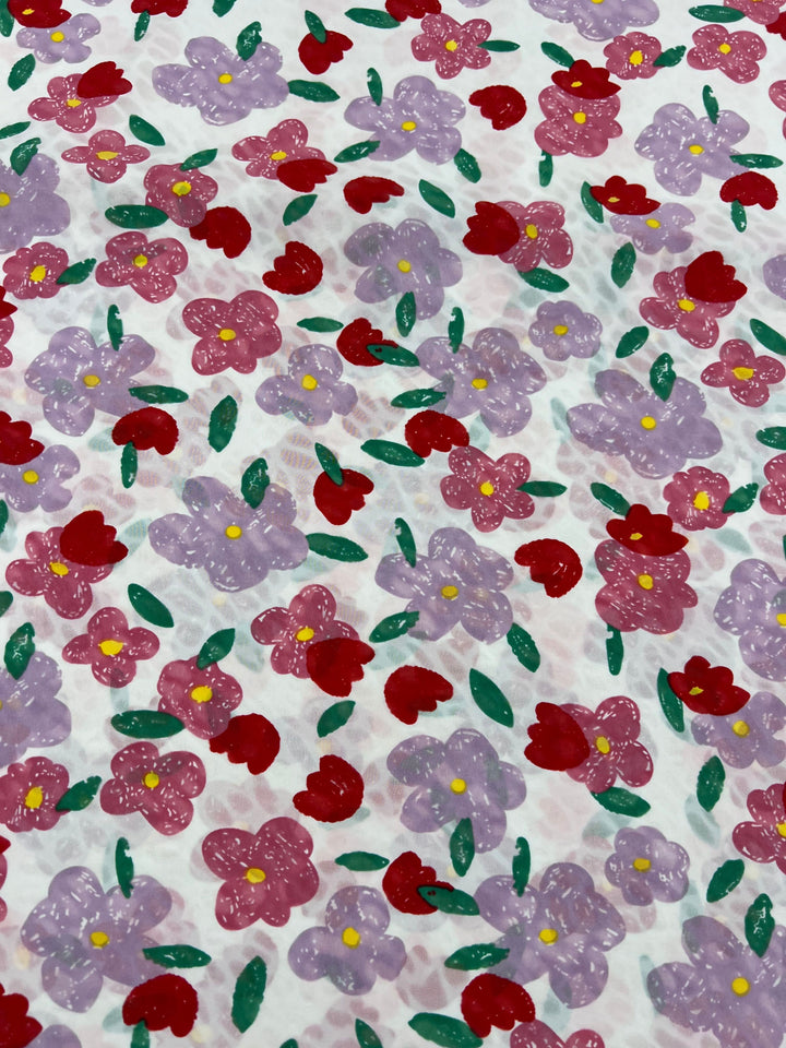 The Salt Shrunk Print - Daise by Super Cheap Fabrics features a colorful floral pattern with pink and purple flowers, green leaves on a light background, and vibrant red accents, creating a cheerful and elegant appearance on 155cm wide fabrics.