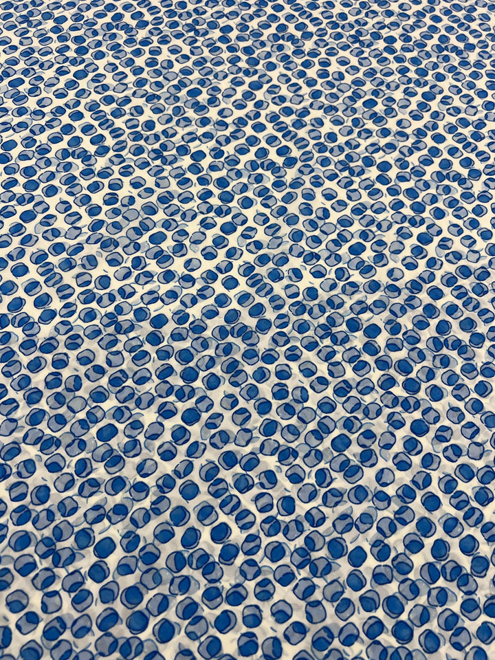 A close-up of a textured pattern showcasing numerous small blue dots on a white background, reminiscent of the vibrant formation in the Salt Shrunk Print - Cells - 155cm from Super Cheap Fabrics, arranged in a wavy, repetitive style.