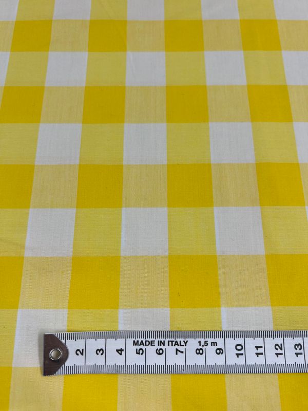 A breathable cotton fabric, featuring a yellow and white checkered print, comes with a measuring tape along the bottom edge marked in centimeters, labeled "Made in Italy." This natural cotton fiber product is known as Cotton Gingham XL - Yellow - 112cm and is offered by Super Cheap Fabrics.